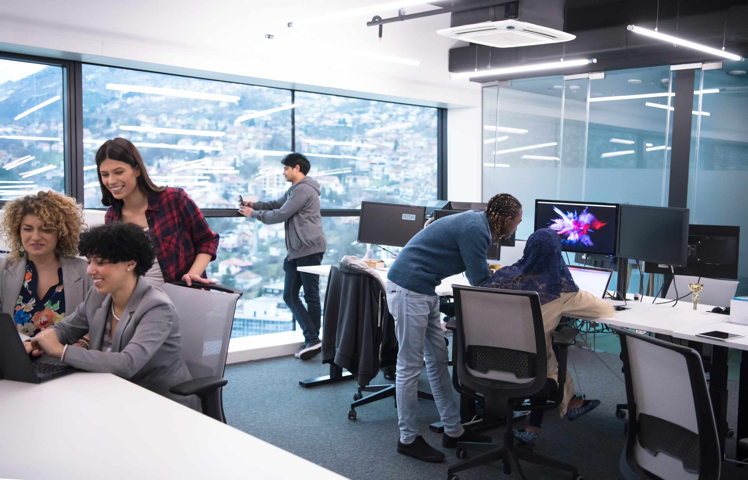 Group of young modern people in formalwear using modern technologies while working in the creative office